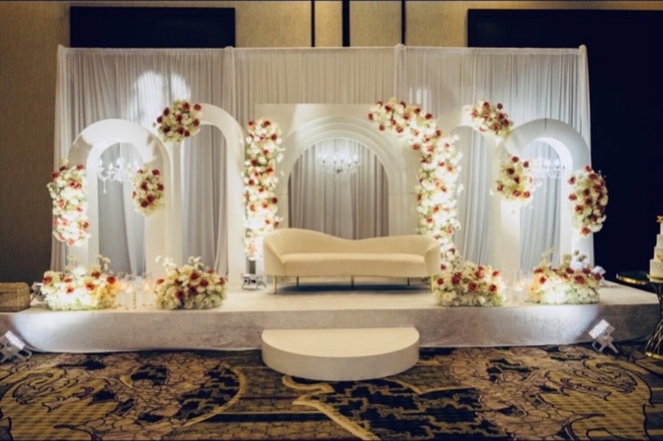 White and red floral arch stage with a cream sofa in a ballroom
